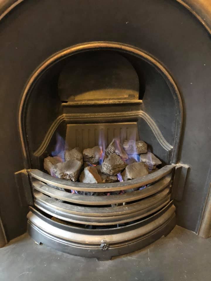 Lit gas fire in a brass-trimmed fireplace