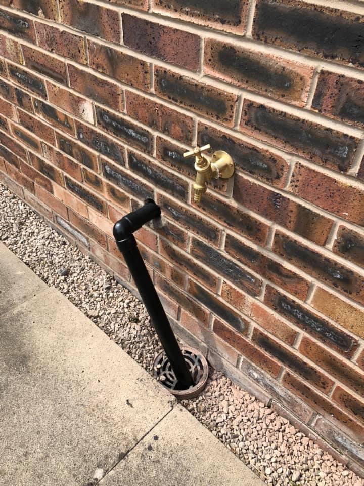 Outside tap and connection against a brick wall